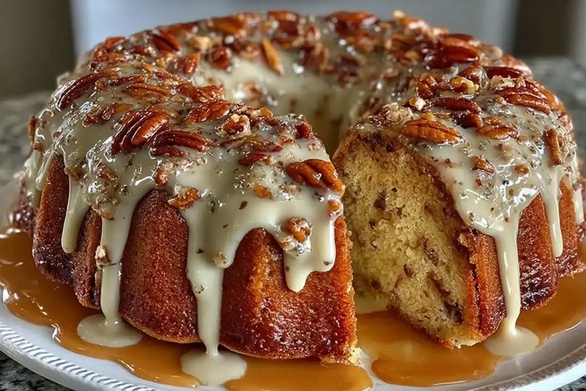 A moist pecan pound cake drizzled with vanilla caramel glaze on a white background.